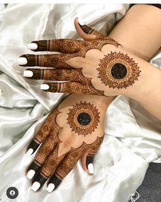 two hands with henna designs on them, one is painted brown and the other is white