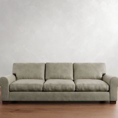 a couch sitting on top of a hard wood floor next to a white painted wall