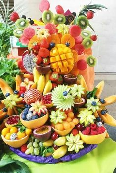 a large display of fresh fruit is displayed on a table with other fruits and vegetables