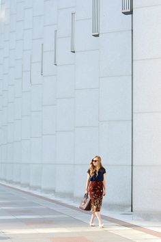 a woman is walking down the street with her hand on her hip while carrying a purse