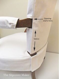 the back of a white chair with an open seat and wooden armrests that are attached to it