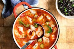 a bowl of chicken and vegetable soup on a wooden table with a spoon in it