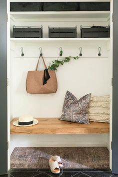 a wooden bench sitting next to a white coat rack filled with purses and hats