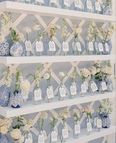 there are many blue and white vases with flowers in them on the shelves next to each other