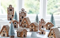 a table topped with lots of small gingerbread houses and trees covered in icing