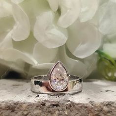 a close up of a ring with a flower in the background