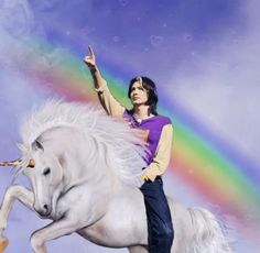 a woman riding on the back of a white unicorn with a rainbow in the background