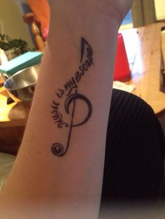 a woman's wrist with a musical note tattoo on it