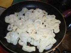 cauliflower being cooked in a wok on the stove