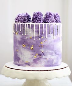 a purple cake with white icing and gold sprinkles on the top