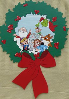 a christmas wreath with cartoon characters on it and a red bow hanging from the front