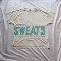 "Vintage 80s SWEATS dd Bi Chego white and blue t-shirt. Size medium, fits oversized. Single stitch. 65% polyester, 35% cotton. Flaws: One dark mark on the front. Note: Longer in back by like half an inch. Care: Machine washable. Measurements  Length: 24.5\" Width: 22\"" Sporty Boxy Fit T-shirt With Screen Print, Oversized Hip Hop Tops With Letter Print, White Drop Shoulder T-shirt With Graphic Print, Sporty Boxy Fit T-shirt For Loungewear, Hip Hop Oversized Slogan Tops, Oversized Hip Hop Tops With Slogans, White Boxy Fit T-shirt With Letter Print, Crew Neck Logo T-shirt For Loungewear, White Boxy Fit T-shirt With Text Print