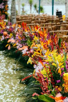 colorful flowers lined up along the side of a road in front of chairs and tables