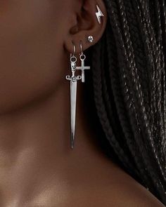 a close up of a person wearing earring designs with scissors in the shape of a cross