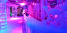 the inside of a building with purple and blue lights on it's walls, along with ice sculptures