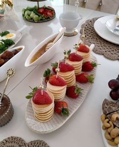 there are many desserts on the table with strawberries and other foods around it