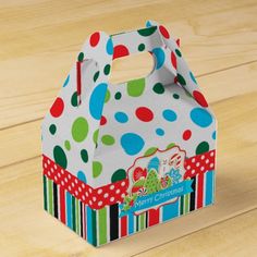 a small white box with colorful polka dots and stripes on the lid, sitting on a wooden surface