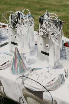 some silver bags are sitting on a table with other items around it and there is a party hat in the middle