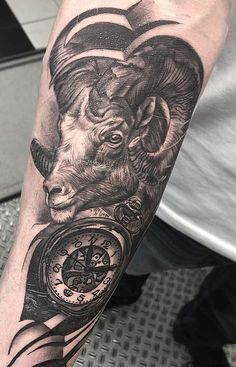 a man with a goat tattoo on his arm holding a pocket watch and looking at the camera