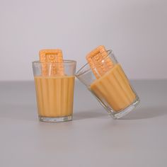 two glasses filled with orange colored liquid sitting next to each other