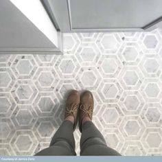 a person wearing brown shoes standing in front of a tile floor with hexagonal tiles