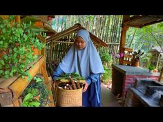 a woman in blue is holding a basket full of plants and vegetables on the porch