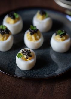 deviled eggs with black cavias and green garnish on a plate