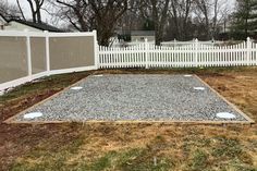 a backyard area with gravel, grass and white picket fence in the backround