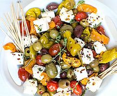 a white plate topped with olives, feta cheese and wooden skewers