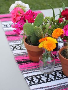 three potted plants on a table with pink, orange and white flowers in them