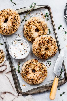 bagels on a baking sheet with cream cheese and sprinkles next to a knife