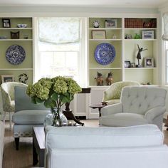 a living room filled with white furniture and lots of bookshelves on the wall