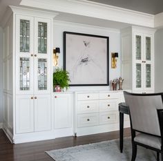 a dining room with white cabinets and a painting hanging on the wall above it's table