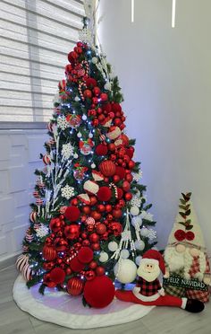 a christmas tree decorated with red and white ornaments is next to a santa clause ornament