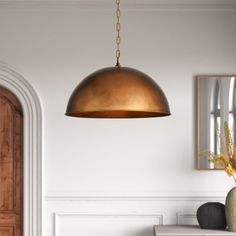 a gold colored light hanging from a ceiling in a room with white walls and furniture