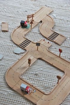 a wooden toy train track with cars and trucks on the tracks next to each other