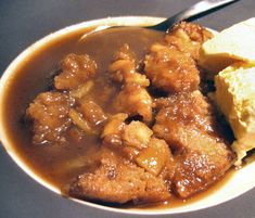 a bowl filled with meat and potatoes covered in gravy on top of a table