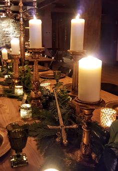 a table topped with candles and greenery on top of a wooden table covered in christmas decorations