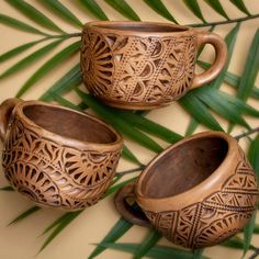 three wooden mugs sitting next to each other on top of a palm tree branch