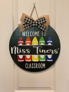 a welcome sign hanging on the front door to a class room with colorful crayons