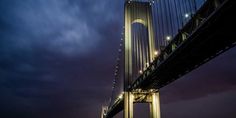 the bridge is lit up at night with lights shining on it's sides and below