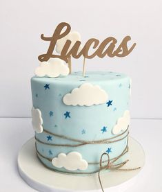 a blue cake with clouds and stars on top that says lucas in wooden letters