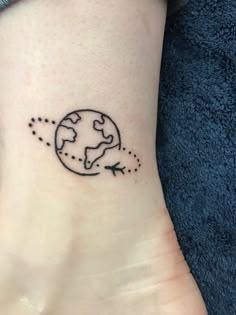 a small tattoo on the ankle of a woman with an airplane flying around the earth