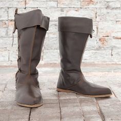 a pair of brown boots sitting on top of a brick floor