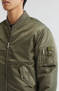 Classic detailing, such a sleeve utility pocket and ribbed trim, authenticates the military-inspired look of this bomber jacket crafted of nylon twill. 25 1/2" length (size Medium) Front zip closure Blade collar Ribbed cuffs and hem Front snap-flap pockets; sleeve utility pocket Lined 100% nylon Dry clean Imported Designer Clothing Green Outerwear With Flap Pockets For Streetwear, Pilot Style Outerwear For Fall Streetwear, Pilot Style Fall Outerwear For Streetwear, Urban Khaki Outerwear With Ribbed Cuffs, Urban Green Outerwear With Cargo Pockets, Olive Utility Jacket With Pockets For Streetwear, Urban Outerwear With Patch Pockets In Nylon, Khaki Outerwear With Ribbed Cuffs For Streetwear, Khaki Nylon Outerwear With Side Pockets