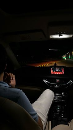 a man sitting in the driver's seat of a car at night