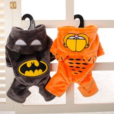 two stuffed animals that are sitting on a window sill, one is wearing a batman costume