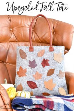 a handbag sitting on top of a chair next to a blanket and pumpkins