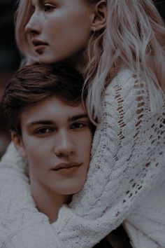 a young man and woman are posing for the camera, one is wearing a white sweater