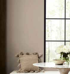 a white table sitting next to a window in a living room with flowers on it